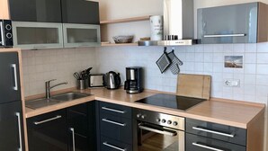 A modern kitchen with black cabinets, a stainless steel oven, a microwave, and a coffee maker. - Traumappartement am Strand by Interhome (Breege)