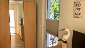 A room with a sliding door leading to a hallway, a window with blinds, a wooden desk with a white bird sculpture, and a wall-mounted sign with text. - Traumappartement am Strand by Interhome (Breege)