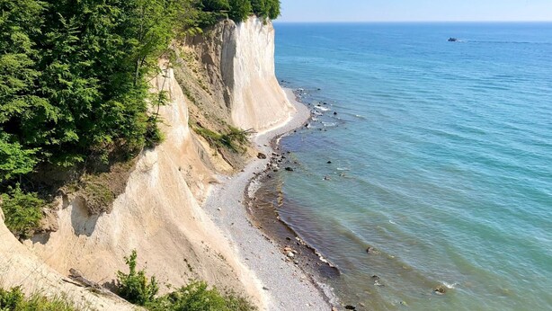 A coastal landscape with a sandy beach, a steep cliff, and a clear blue sea. - Traumappartement am Strand by Interhome (Breege)