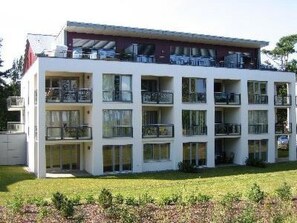 Ein mehrstöckiges Gebäude mit Balkonen, großen Fenstern und einem flachen Dach.