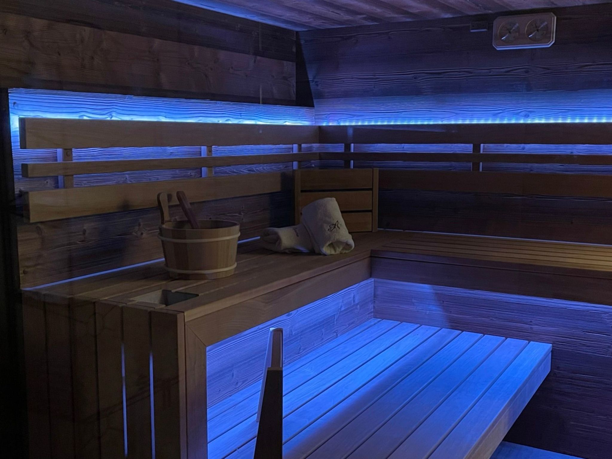 A sauna with wooden benches and a bench with a towel.
