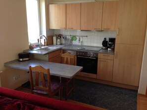 Eine kleine Küche mit Holzausbau, Backofen, Spüle und einem Essbereich mit Tisch und Stühlen.