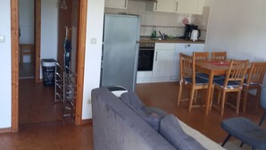 Ett kompakt bostadsutrymme med en soffa, ett matbord och ett köksområde.