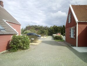 Une rue résidentielle bordée de maisons, avec une allée pavée et une voiture garée.