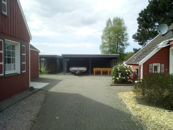 A covered outdoor area with a bench, a small table, and a truck parked. - Kleine Ferienwohnung in ruhiger Lage by Interhome (Westoverledingen)
