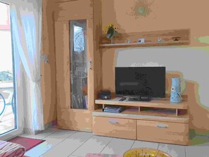 Une pièce avec un téléviseur posé sur un meuble en bois, une porte avec un panneau de verre et une petite étagère sur laquelle se trouve un vase.