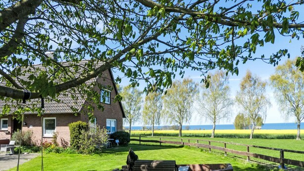 Een huis met een schommel en een boot in de tuin.