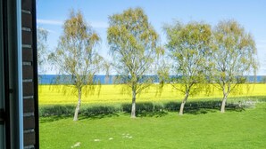 Een uitzicht over een grasveld met bomen en een verre waterpartij.