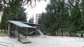 Un'area giochi con uno scivolo, altalene e una zona relax coperta.