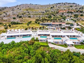 Et moderne resort med flere swimmingpools, udsigt fra en skråning og en blanding af boliger og erhvervsejendomme.
