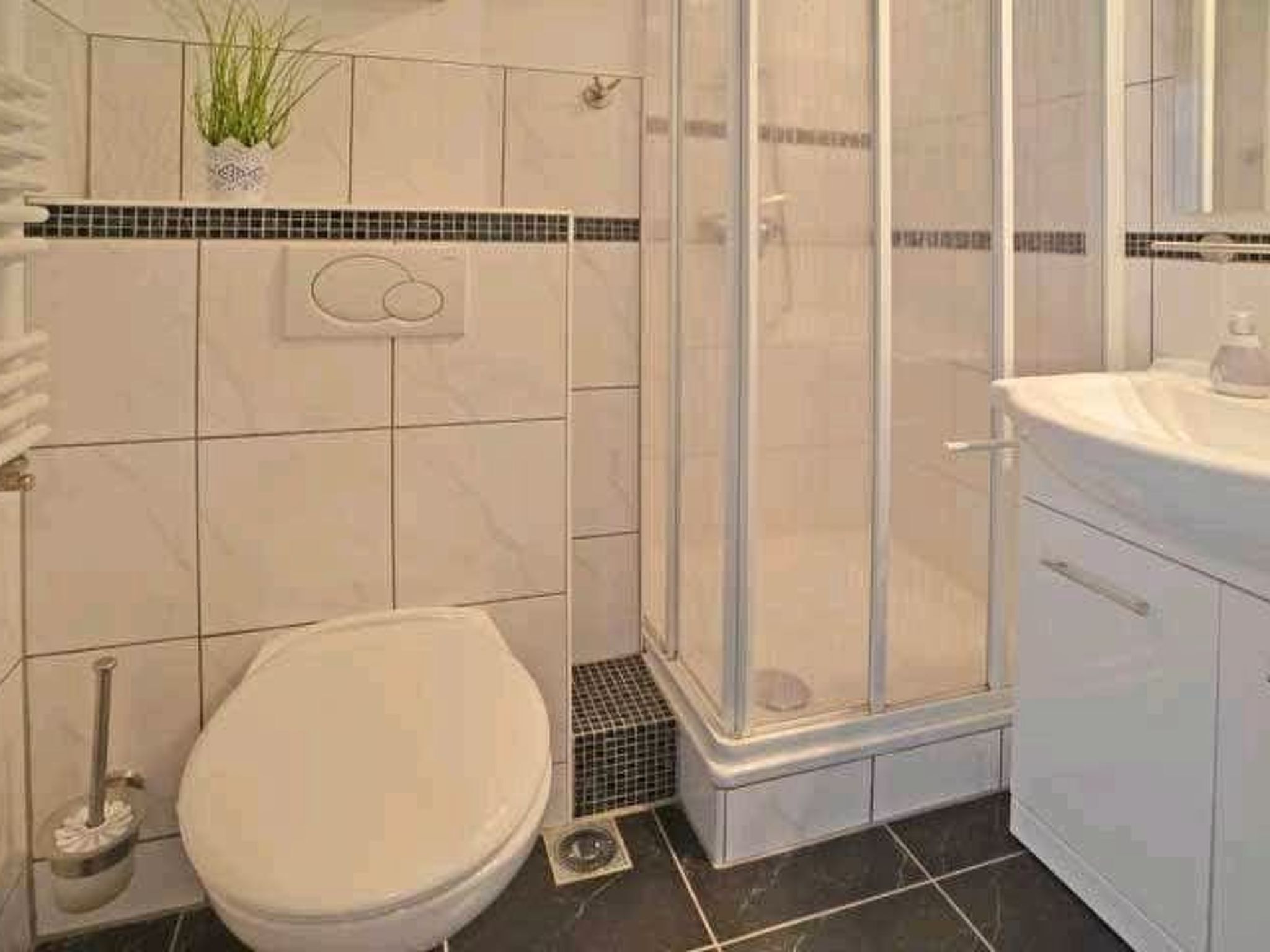 A bathroom with a toilet, a shower enclosure, and a sink.