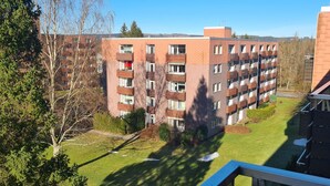 En flervåningsbyggnad med bostäder, balkonger, en grön innergård och omgivande träd.