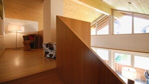 Ein modernes Interieur mit einer Holztreppe, einem Sofa, einer Lampe und einem Ottomanen mit Kuhmuster.