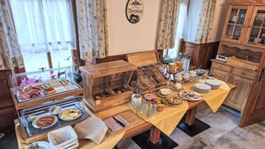 Ein Frühstücksbuffet mit verschiedenen Speisen, einem Holzschrank und einer Wanduhr.