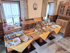 Un buffet de petit-déjeuner proposant divers aliments, un buffet en bois et une horloge au mur.