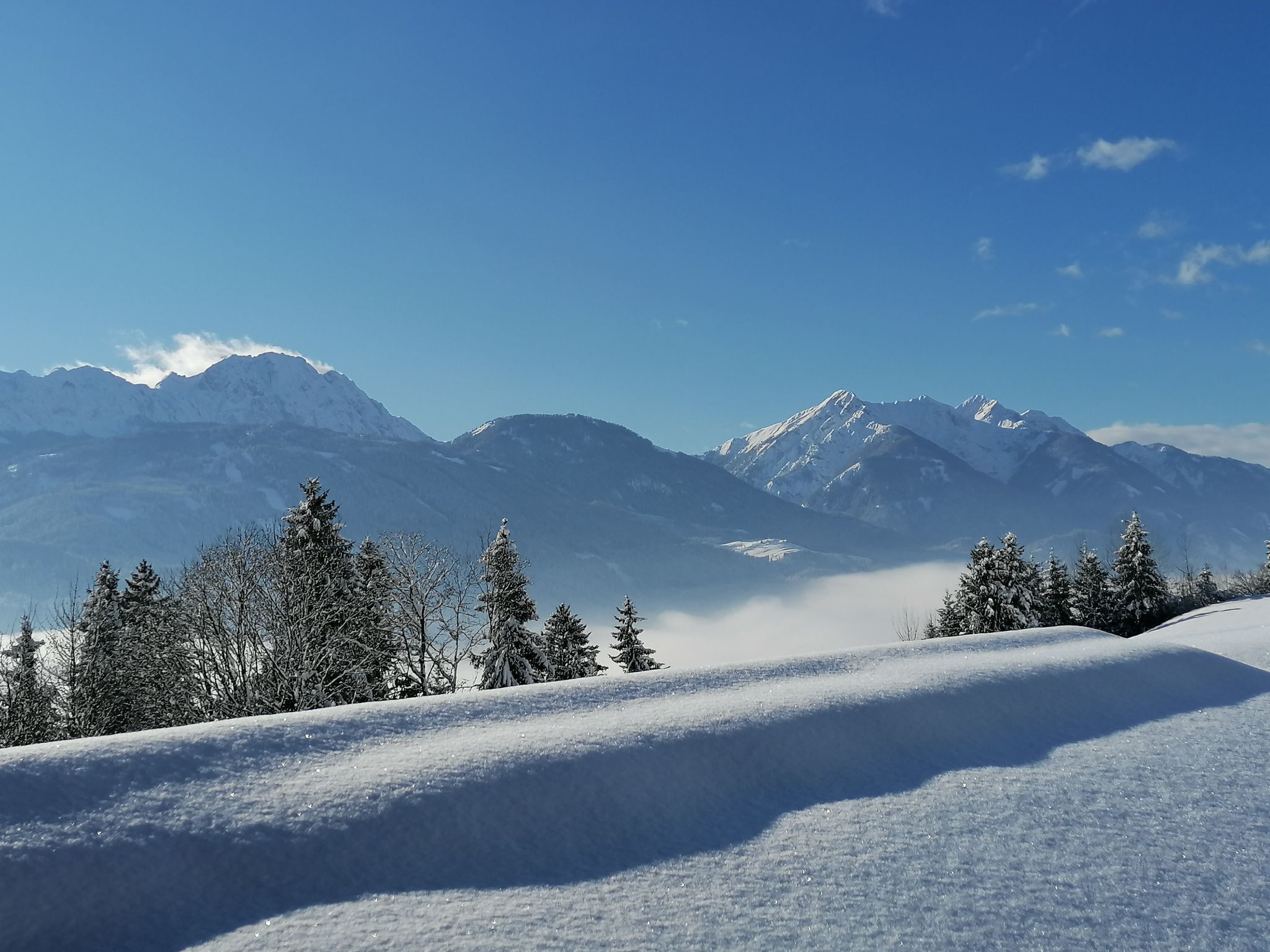 Un paisaje montañoso cubierto de nieve con cielos despejados.