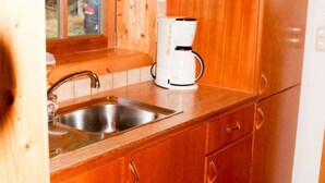 Uma cozinha com armários de madeira, pia de aço inoxidável e máquina de café branca.