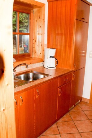 Eine Küche mit Holzausstattung, einem Edelstahl-Spülbecken und einer weißen Kaffeemaschine.