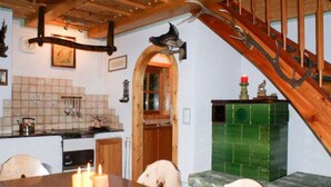 Decoração rústica com escada de madeira, área de jantar com mesa posta para dois e um armário verde.