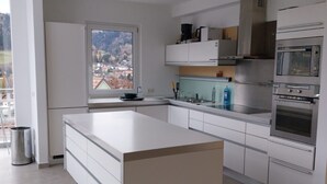 Una cocina moderna con armarios blancos, una isla grande y electrodomésticos integrados, incluyendo estufa y horno.