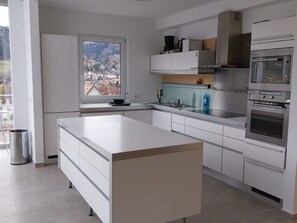 A modern kitchen with white cabinetry, a large island, and built-in appliances including a stove and oven. - Haus Kreischberg by Interhome (Sankt Georgen am Kreischberg)