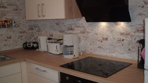 Une cuisine équipée d’une plaque de cuisson à induction noire, d’un grille-pain, d’une machine à café et d’une radio.