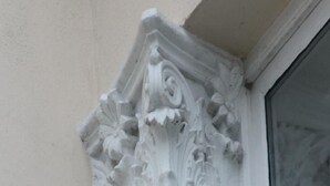 Eine Gebäudeecke mit dekorativer Sandsteingesimse mit floralen Reliefs.
