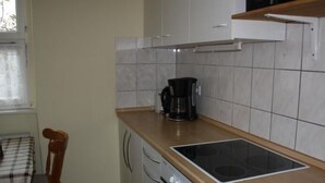 Eine Küche mit Herd, Kaffeemaschine und einem Esstisch mit Stuhl.