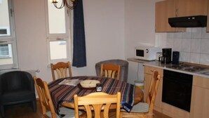 A small, cozy kitchen with a round wooden table, four wooden chairs, a microwave, a coffee maker, and a dishwasher. - in Strandnähe in Ahlbeck by Interhome (Ahlbeck)