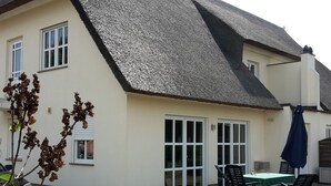 A house with a thatched roof, a patio with a table and chairs, and a car parked nearby. - Tante Waltraut in Garz auf Usedom by Interhome (Ahlbeck)