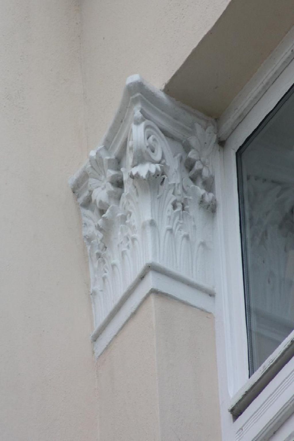 A building corner with a decorative stone cornice featuring floral carvings.