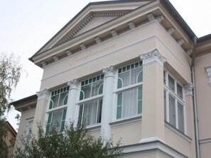 Un edificio de arquitectura clásica, con una entrada destacada que incluye columnas y un frontón.