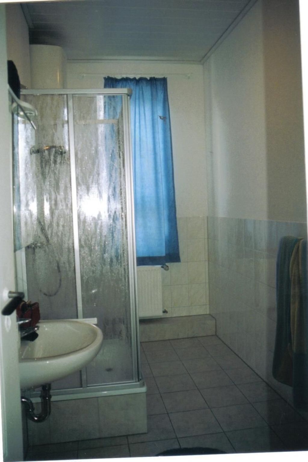 Une salle de bain avec une douche à parois de verre, un lavabo et un rideau bleu.
