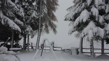 Un parque cubierto de nieve con un columpio y bancos.