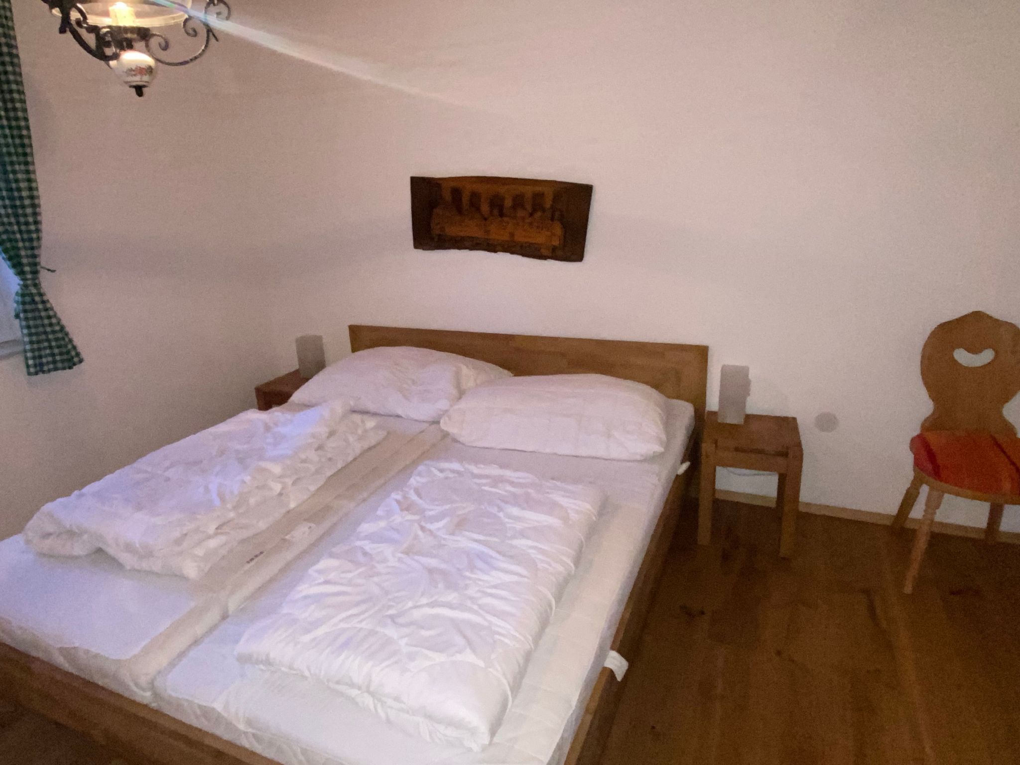 A neatly made bed with white linens, a wooden headboard, and a small bedside table with a lamp.