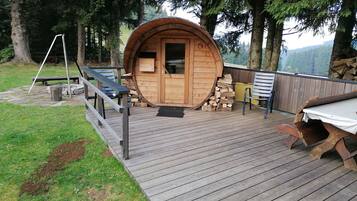 A wooden barrel-shaped cabin with a door, a deck, and a bench.