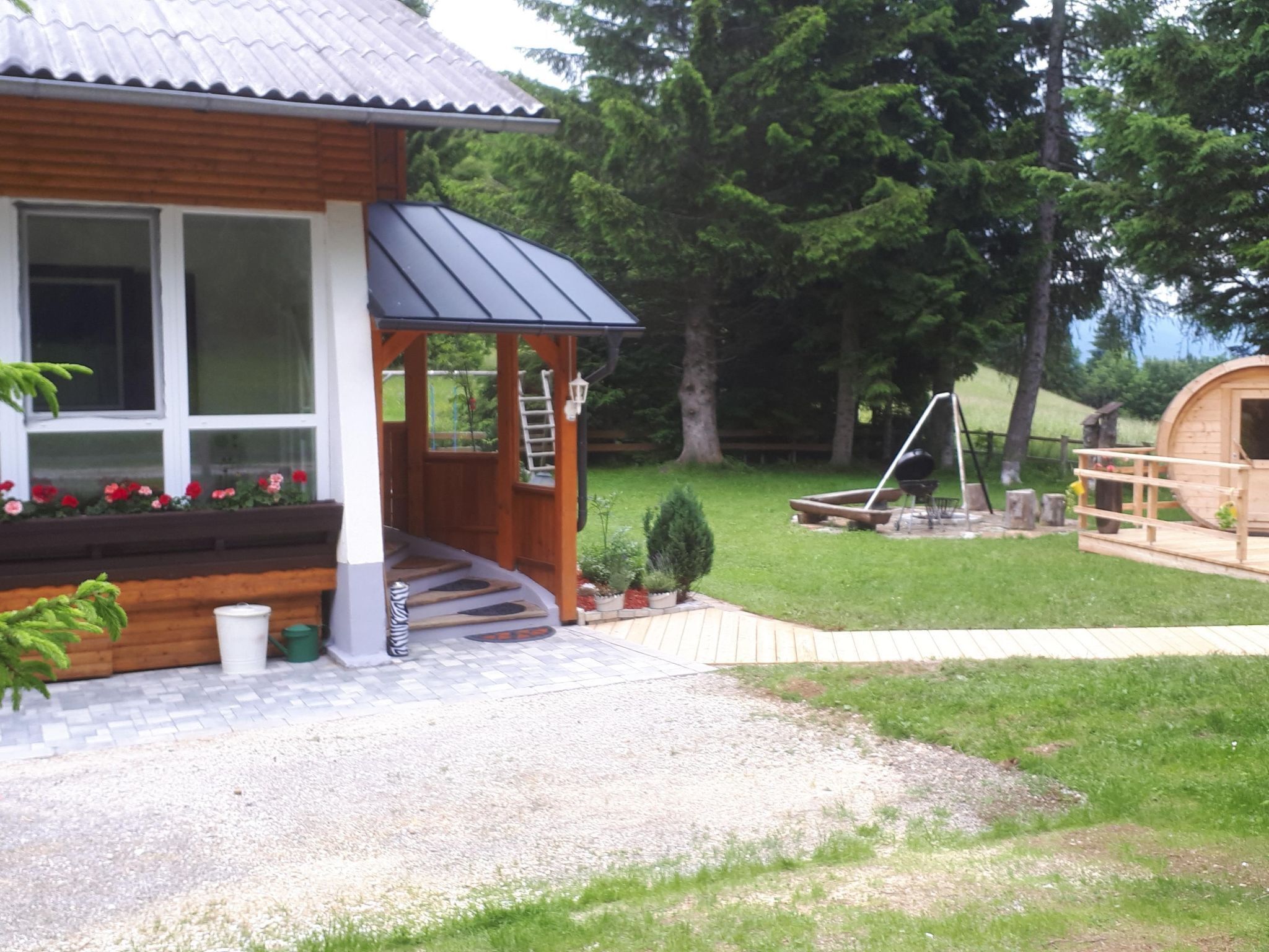 Une cabane en bois avec un porche, un petit jardin et une terrasse en bois.