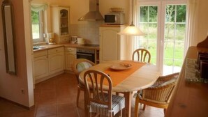 A kitchen with a dining table, chairs, and a view of the garden through the window. - Kliffkieker by Interhome (Ahlbeck)
