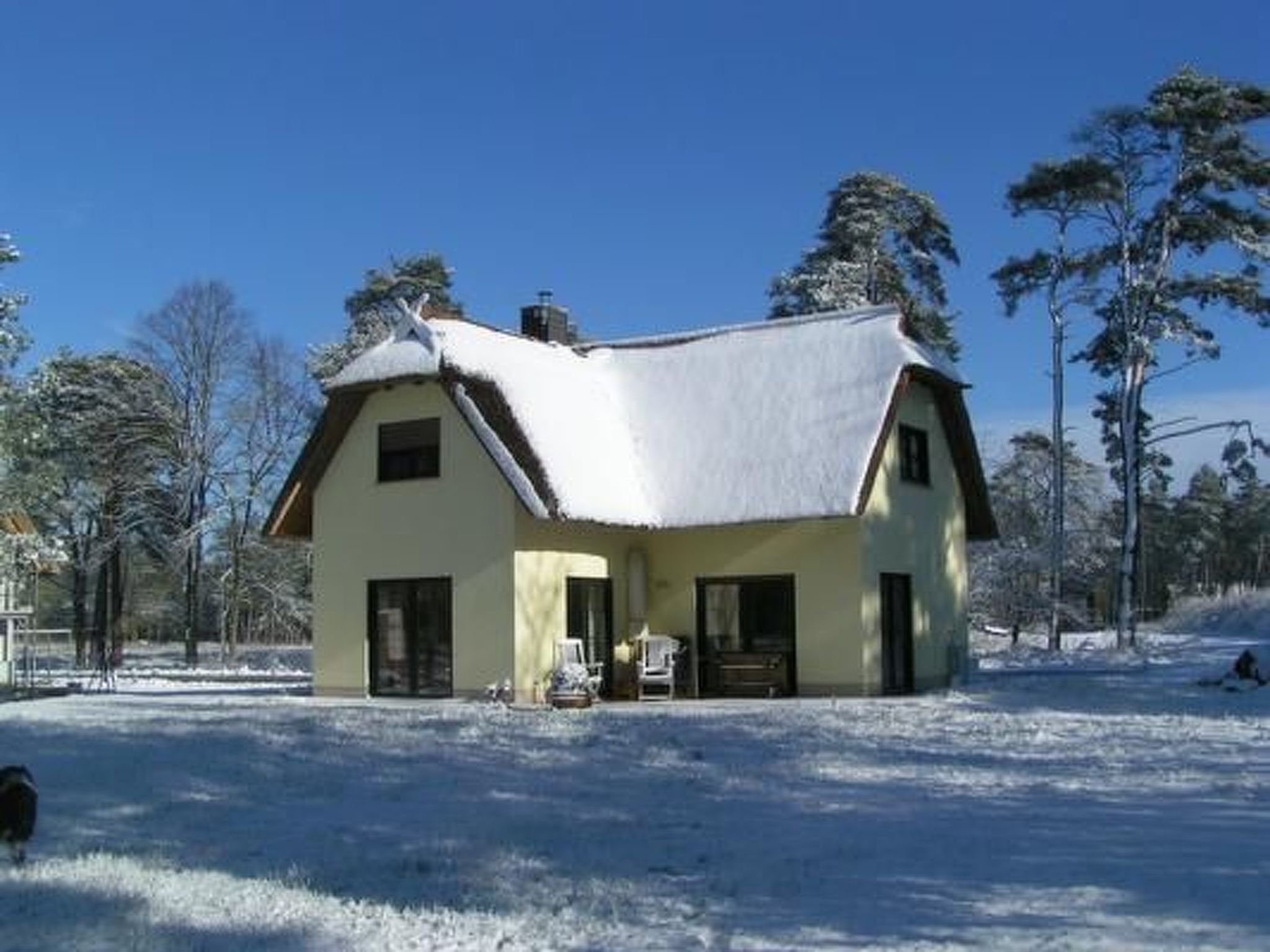 A house with a snow-covered roof, a front porch, and a yard.