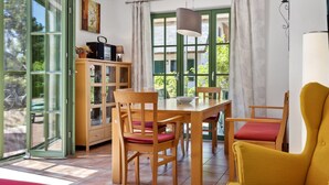 Un espacio habitable de concepto abierto con zona de comedor, un sillón amarillo y vistas amplias a través de grandes ventanales.