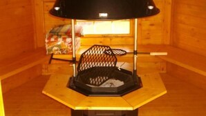 Interior de madera con un radiador negro, un banco y una ventana con cortinas.