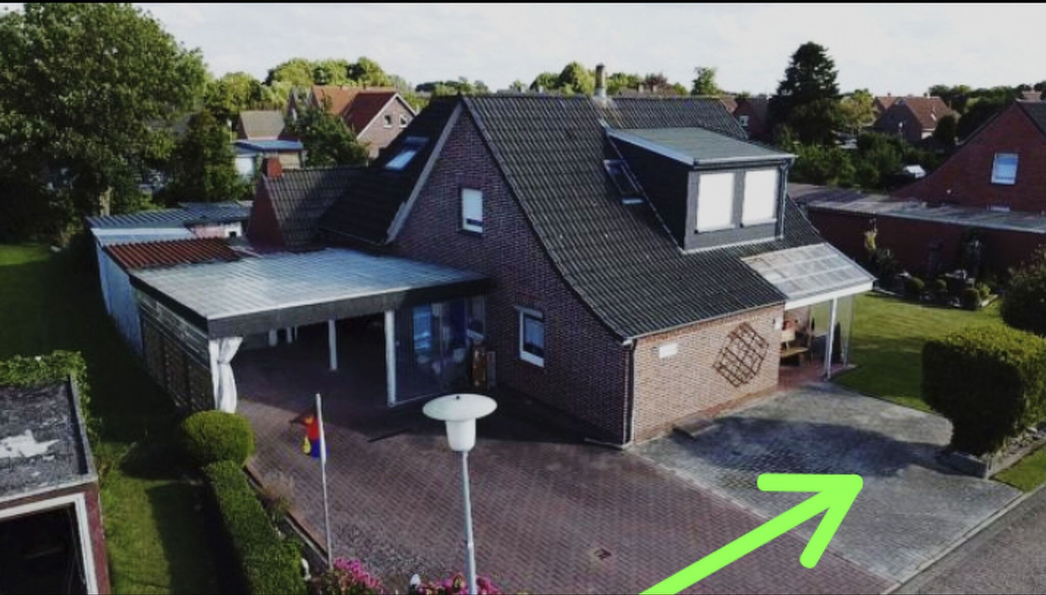 A two-story house with a sloped roof, a front porch, and a small garden area.