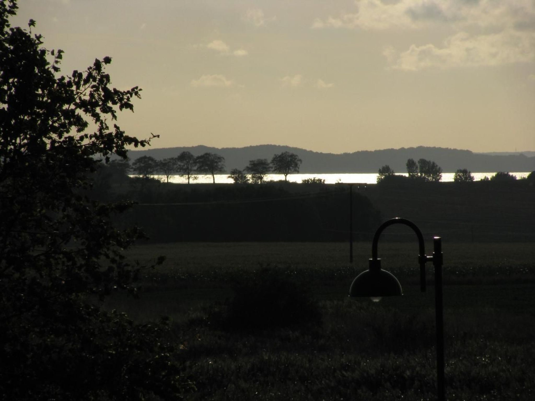 Een landelijk landschap met een waterpartij, bomen en een metalen constructie op de voorgrond.