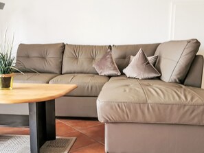 A sectional sofa with a wooden table and a potted plant. - Zeesenhaus 6 by Interhome (Ostseebad Sellin)