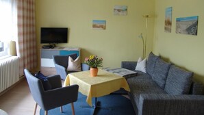 A room with a sofa, a table with a yellow tablecloth, a TV, and a window with curtains. - Uns Oellernhuus by Interhome (Karlshagen)