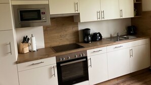 Une cuisine moderne avec des meubles blancs, un four à micro-ondes en acier inoxydable, une machine à café et un four.