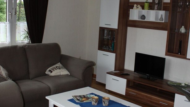 Un salon moderne comprenant un canapé, une table basse, un téléviseur et des étagères intégrées.