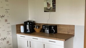 Une cuisine compacte avec un plan de travail en bois, une machine à café et un panneau fixé au mur.