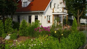 A two-story house with a red roof, white walls, and a balcony with wooden railings. - Wohnung in Abbehausen - Ellwürden by Interhome (Abbehausen)