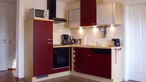 A compact kitchen with a microwave, oven, and coffee maker. - Wohnung in Abbehausen - Ellwürden by Interhome (Abbehausen)